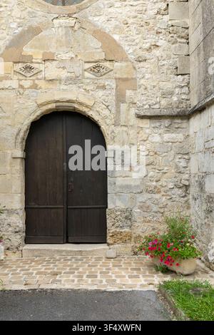 Porta in legno rustica ad arco con arco in pietra inserita in un'antica parete di pietra consumata Foto Stock