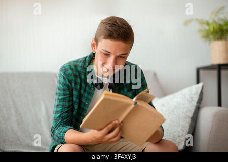 Ragazzo teenager che gode il suo libro, che passa il tempo a casa Foto Stock