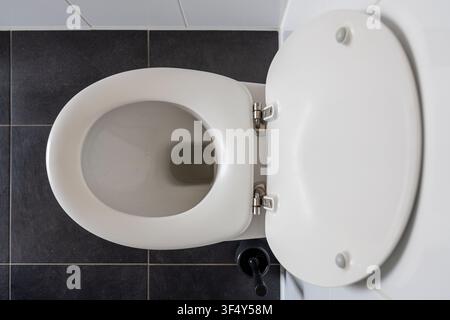 toilette a muro con il coperchio completamente aperto nel bagno Foto Stock