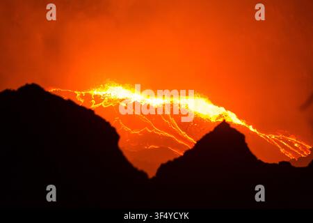 Vista del lago di lava incandescente del vulcano Erta Ale con roccia fusa che trabocca dal bordo del cratere nell'oscurità della notte nella Zona 2, Afar, Etiopia Foto Stock