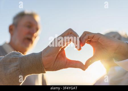 Il cuore dell'amore forma la pace. Coppia anziana che si forma il cuore con le mani. Moglie di vecchio marito adulto che mostra segno di cuore. Felice famiglia pensionato. Ti amo buon giorno di San Valentino Foto Stock