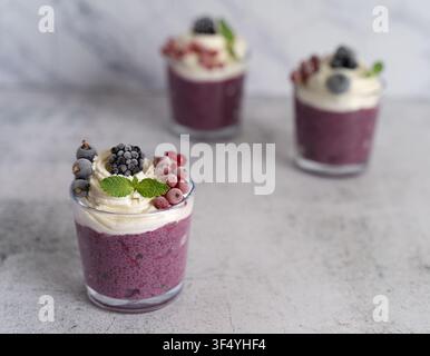 Pudding di chia ai frutti di bosco sano servito in bicchieri e guarnito con panna montata e frutti di bosco freschi Foto Stock
