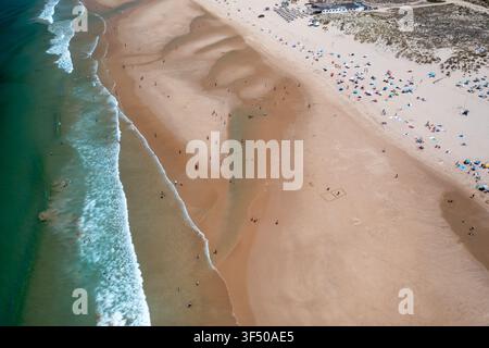 Vista aerea dall'alto di una vasta spiaggia sabbiosa con dolci onde dell'oceano che raggiungono la riva. Foto Stock