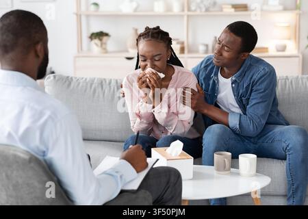Giovane donna nera che grida all'incontro con il consigliere di famiglia, marito che la conforta Foto Stock
