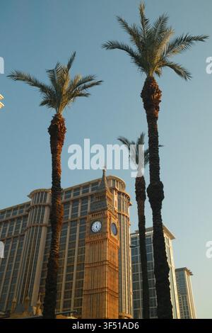 Scatto verticale a basso angolo della replica dell'Elizabeth Tower Big Ben incorniciata da alte palme al resort The Londoner Macao a Macau, Cina. Foto Stock