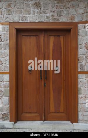 Porta di legno con battenti a testa di leone in muro di pietra Foto Stock