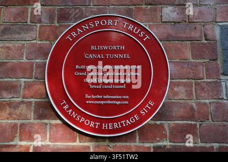 Una targa commemorativa circolare rossa del Transport Trust che segna il tunnel storico del canale di Blisworth come sito patrimonio su un muro di mattoni rossi nel Regno Unito Foto Stock