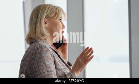 Esperta donna manager impegnata in una seria telefonata, comunica informazioni importanti mentre gesticola, rappresentando il moderno Foto Stock