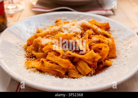 Pasta tagliatelle con salsa bolognese e formaggio grattugiato su un tavolo Foto Stock