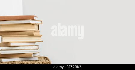 Pila di vecchi libri con copertine bianche su un cesto intrecciato, concetto di educazione e conoscenza, sfondo di lettura e apprendimento Foto Stock