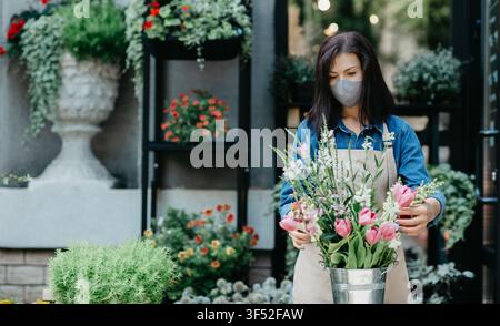Fiorista che organizza bouquet di bellissimi fiori colorati in negozio Foto Stock