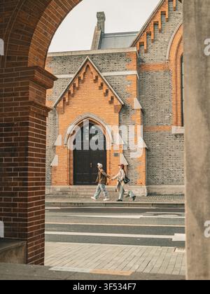 Coppia che si tiene per mano attraversando la strada davanti alla Union Church, Shanghai Foto Stock