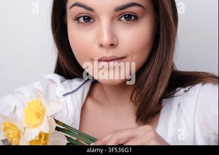 Donna bruna che tiene giunchiglie in studio Foto Stock