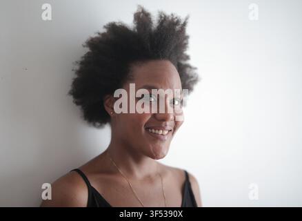 Donna nera amichevole con un afro che sorride luminosamente Foto Stock