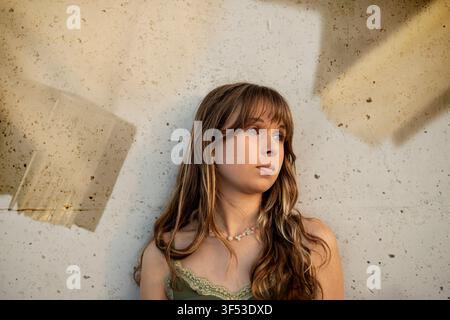 giovane donna che guarda lontano vicino a un muro di cemento Foto Stock