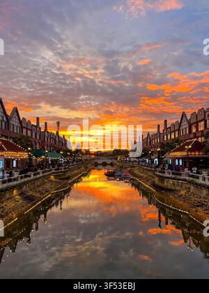 Tramonto dorato sul canale in stile europeo a La Riviera PIK 2 a Tangerang, Indonesia, che riflette nuvole infuocate mozzafiato. Foto Stock