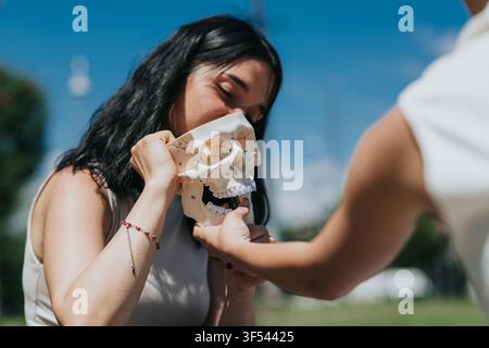Studenti che esaminano un modello di anatomia del cranio umano durante una lezione di anatomia all'aperto nel campus Foto Stock
