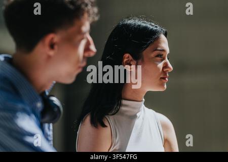 Giovane studentessa di profilo con uno studente maschio sfocato accanto a lei nel campus Foto Stock
