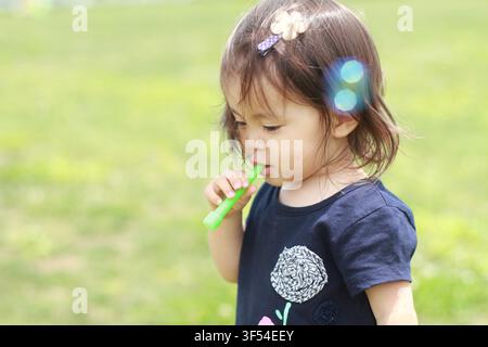 Ragazza giapponese che gioca con una bolla (1 anno) Foto Stock