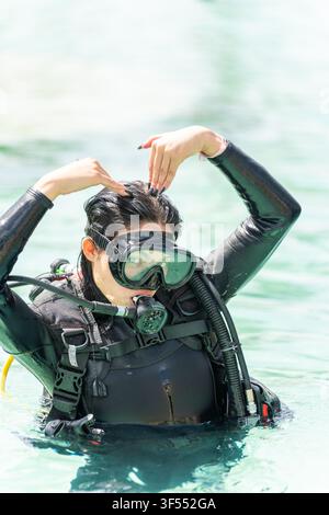 Donna in muta subacquea e attrezzatura per immersioni che si prepara per fare immersioni subacquee o snorkeling Foto Stock