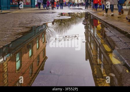Fotografia creativa a bassa angolazione della strada che cattura riflessi colorati dopo la pioggia nella città storica di York, Inghilterra, Regno Unito Foto Stock
