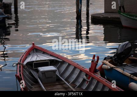 Barche di legno tradizionali ormeggiate su acque calme al tramonto in un piccolo porto sul Lago di Garda, Italia. Foto Stock
