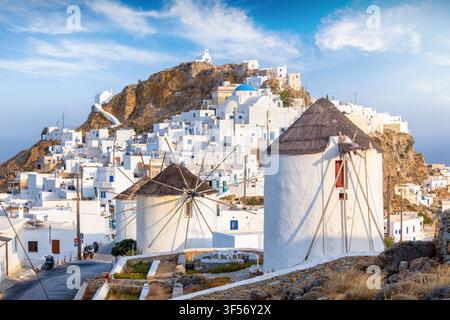 La bellissima città dell'isola di Serifos, Cicladi, Grecia, con case imbiancate a calce e mulini a vento su una montagna durante il tramonto estivo Foto Stock