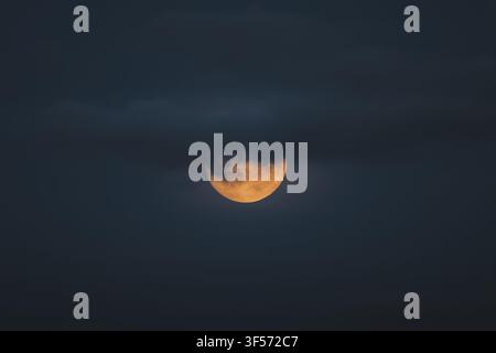 Vista della luna parzialmente oscurata da nuvole scure di notte a Merikula, Harju maakond, Estonia. Foto Stock