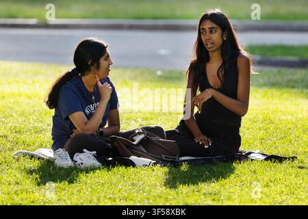 Due donne sedute a chiacchierare sull'erba del Boston Common, Boston, Massachusetts. Foto Stock