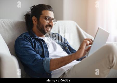 Happy Western uomo che controlla i social media su tablet digitale a. casa Foto Stock