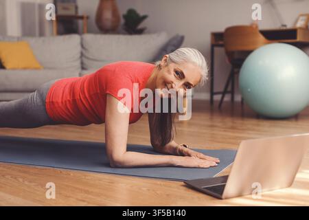 Donna anziana sorridente che fa l'esercizio della panca a casa, concetto di fitness Foto Stock