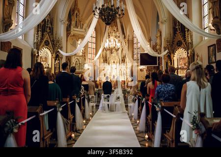 Jablonowo Pomorskie, Polonia – 6 settembre 2025: Elegante cerimonia nuziale in una grande chiesa storica. Vista posteriore della sposa, dello sposo e degli invitati al matrimonio. Matrimonio tradizionale, interno di una chiesa cattolica Foto Stock