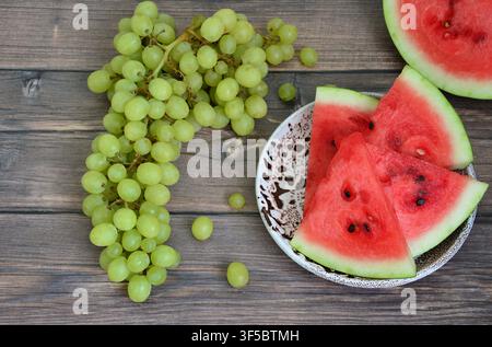 un flat lay di uva verde fresca e anguria affettata su un tavolo di legno Foto Stock