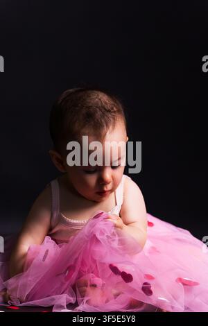 Adorabile bambina in tutù rosa che gioca con i cuori Foto Stock