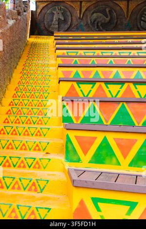 Scalinata luminosa decorata con vivaci motivi tribali geometrici in giallo, verde e arancione. Dettaglio architettonico colorato accattivante con simmetria Foto Stock