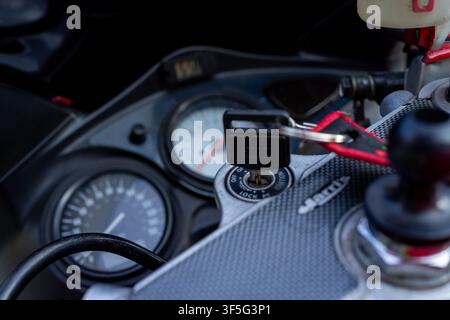 La chiave di accensione della moto riposa nel suo alloggiamento. Il cluster degli strumenti mostra il tachimetro e il contagiri. Una manopola di controllo e una cornice in filo rosso incorniciano la vista. Superficie metallica Foto Stock