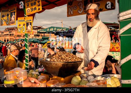 Bella vista serale di uno chef che vende lumache fresche a turisti e locali nella piazza Jemaa el-Fnaa del quartiere della Medina a Marrakech, Marocco Foto Stock
