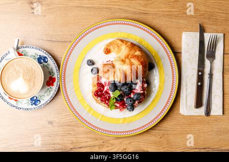 Sandwich croissant alla moda con formaggio burrata, bacche fresche e caffè Foto Stock