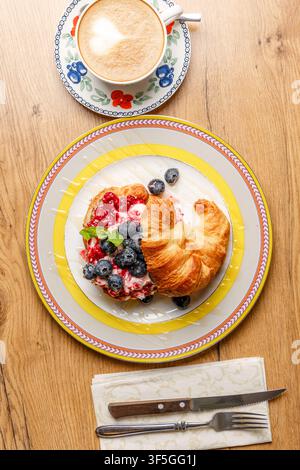 Sandwich croissant alla moda con formaggio burrata, bacche fresche e caffè Foto Stock