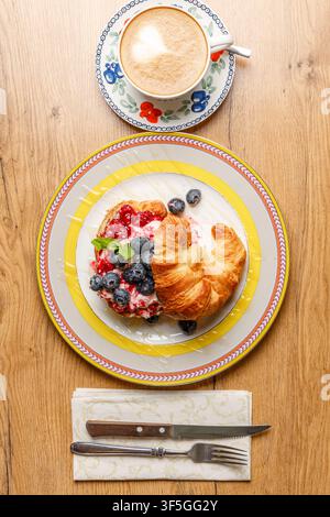 Sandwich croissant alla moda con formaggio burrata, bacche fresche e caffè Foto Stock