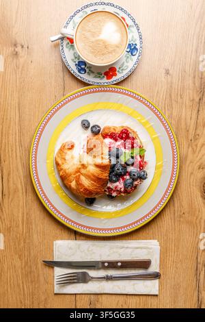 Sandwich croissant alla moda con formaggio burrata, bacche fresche e caffè Foto Stock