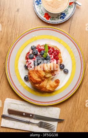 Sandwich croissant alla moda con formaggio burrata, bacche fresche e caffè Foto Stock