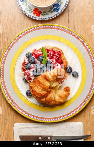 Sandwich croissant alla moda con formaggio burrata, bacche fresche e caffè Foto Stock