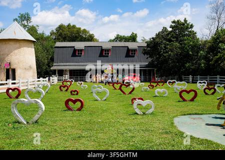 Pekanbaru, Indonesia - 8 dicembre 2024: Una foto scenografica all'aperto di Asia Farm con decorazioni a forma di cuore, un fienile e un mulino a vento sotto un cielo luminoso Foto Stock