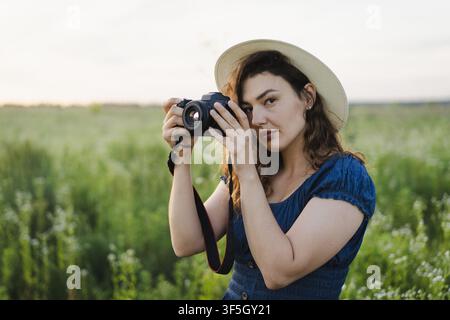Fotografa sorridente che rivede le foto sulla fotocamera in un prato estivo Foto Stock