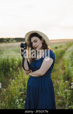 Fotografa sorridente che rivede le foto sulla fotocamera in un prato estivo Foto Stock