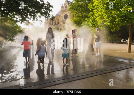 Bambini che si rinfrescano nelle fontane a nebbia d'acqua del Jardin Nelson Mandela a Parigi, Francia Foto Stock