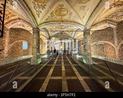 Grande corridoio ad arco con affreschi intricati sul soffitto. Mura in pietra rivestite di motivi a mosaico. Un'illuminazione calda evidenzia l'architettura storica. Pochi visitatori Foto Stock