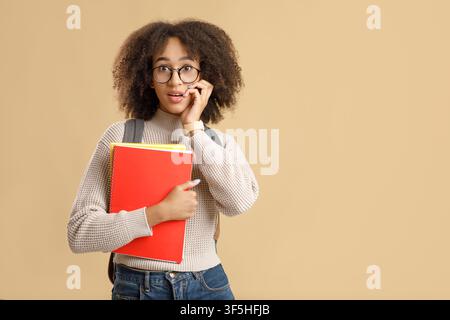 Emozioni umane eccitate. Donna afro-americana stupita con occhiali di ritorno a scuola Foto Stock