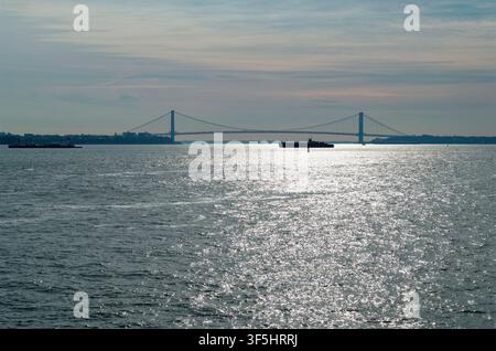 La luce del sole brilla sul porto di New York mentre il ponte di Verrazzano-Narrows si estende all'orizzonte Foto Stock